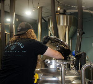 Mikey on a ladder adding ingredient to a tank