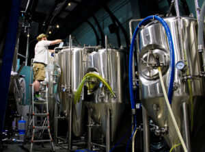 Mikey on a ladder adding ingredient to a tank
