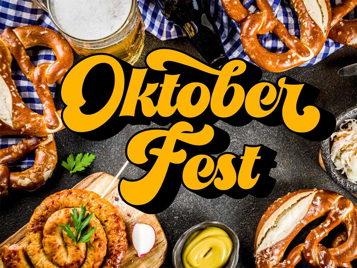 Oktober Fest sign in bold yellow script, surrounded by pretzels, beer, and mustard on a dark surface with a blue checkered cloth.